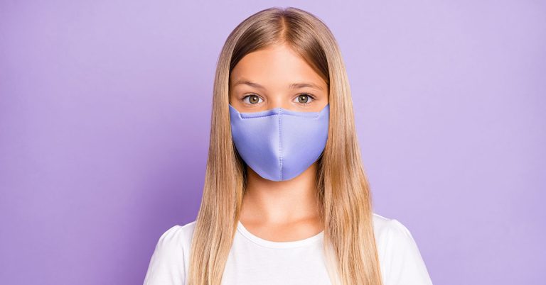 Close up photo of pretty positive cheerful child look have covid-19 quarantine her family friends wear white breathing mask t-shirt clothes isolated over violet color background